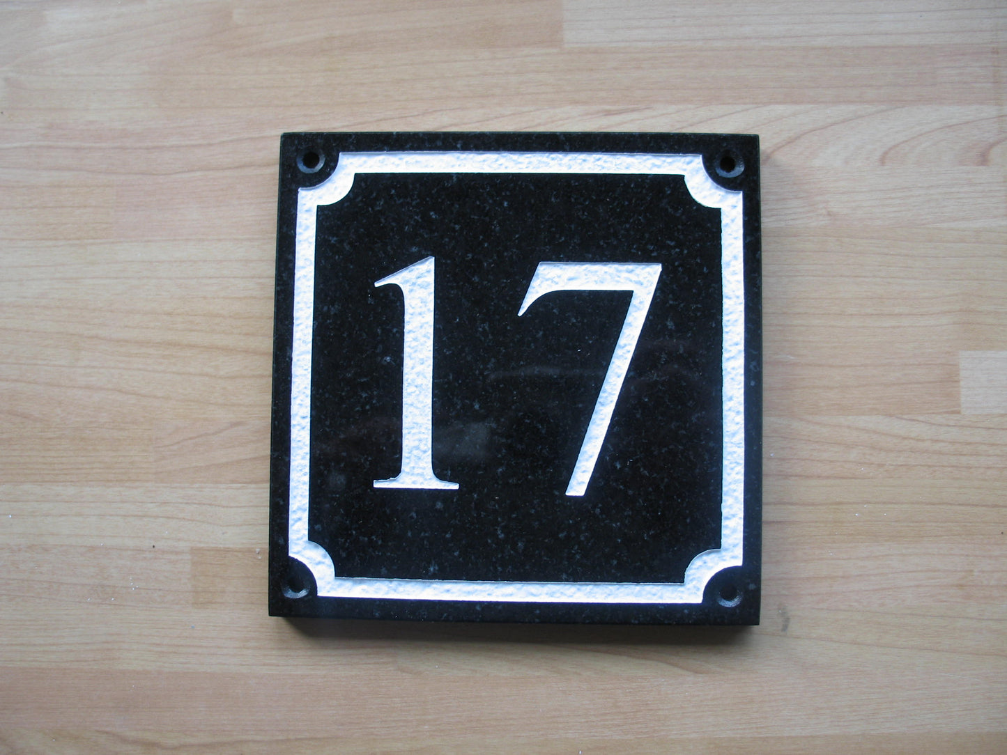 House number sign measuring 150mm x 150 mm using black Corian with a scalloped border and the address deep engraved and infilled with white monument paint