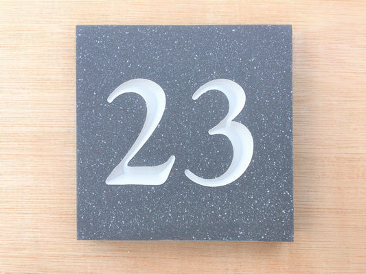 House sign measuring 100mm x 100mm using grey Corian with the house number 23 deep engraved and infilled with white monument paint