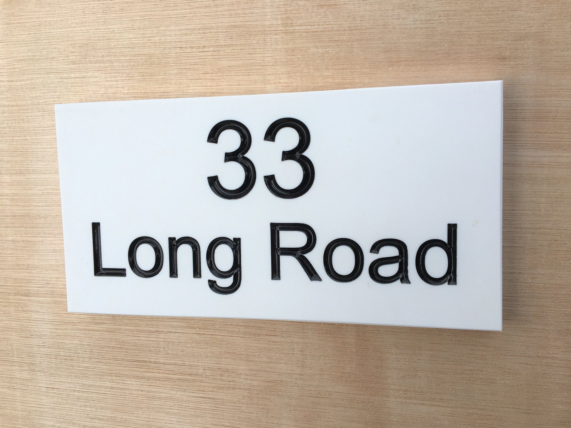 House sign measuring 200mm x 100mm using white Corian with the address and number 33 deep engraved and infilled with black monument paint