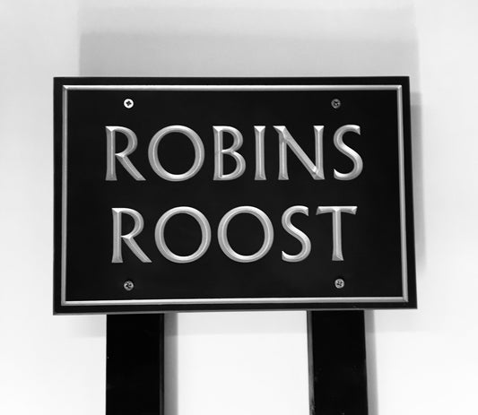 House sign measuring 300mm x 200mm using black Corian with a plain border and the house name  deep engraved and infilled with silver monument paint mounted on a black post 