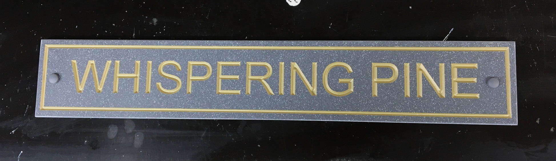 House sign measuring 600mm x 100mm using grey Corian with a plain border and the address deep engraved and infilled with gold monument paint