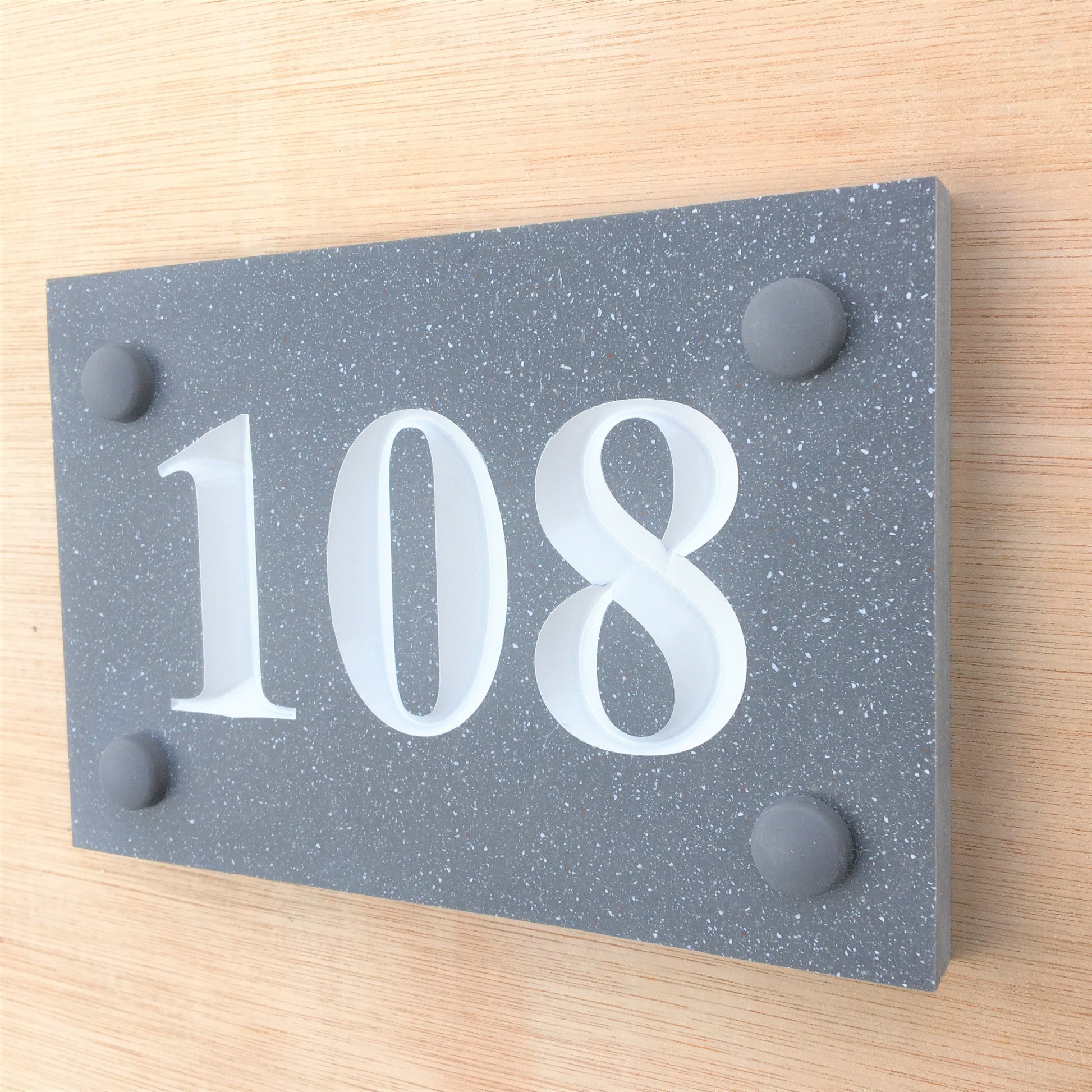 House sign measuring 150mm x 100mm using grey Corian with the house number 108 deep engraved and infilled with white monument paint