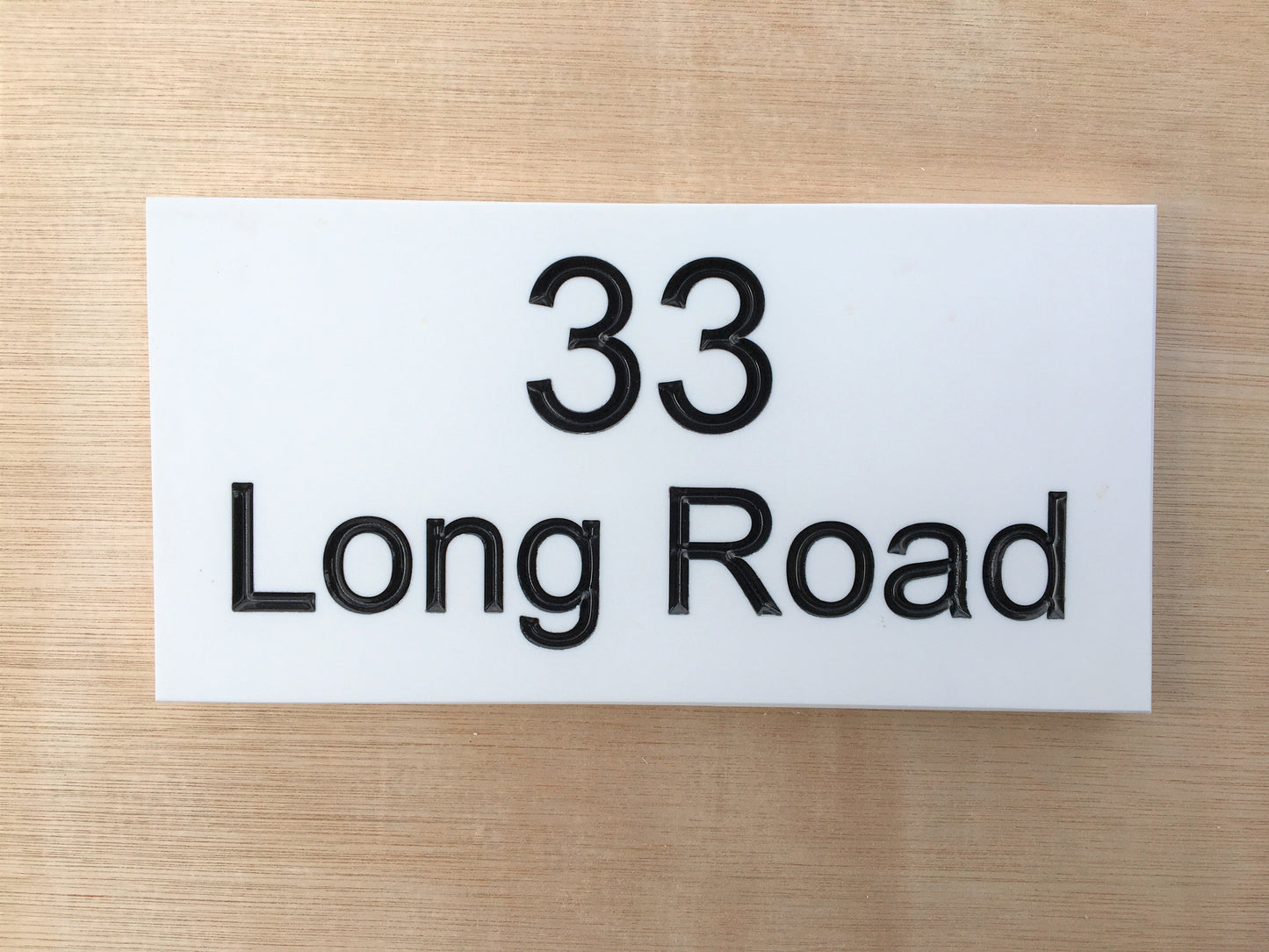 House sign measuring 200mm x 100mm using white Corian with the address and number 33 deep engraved and infilled with black monument paint