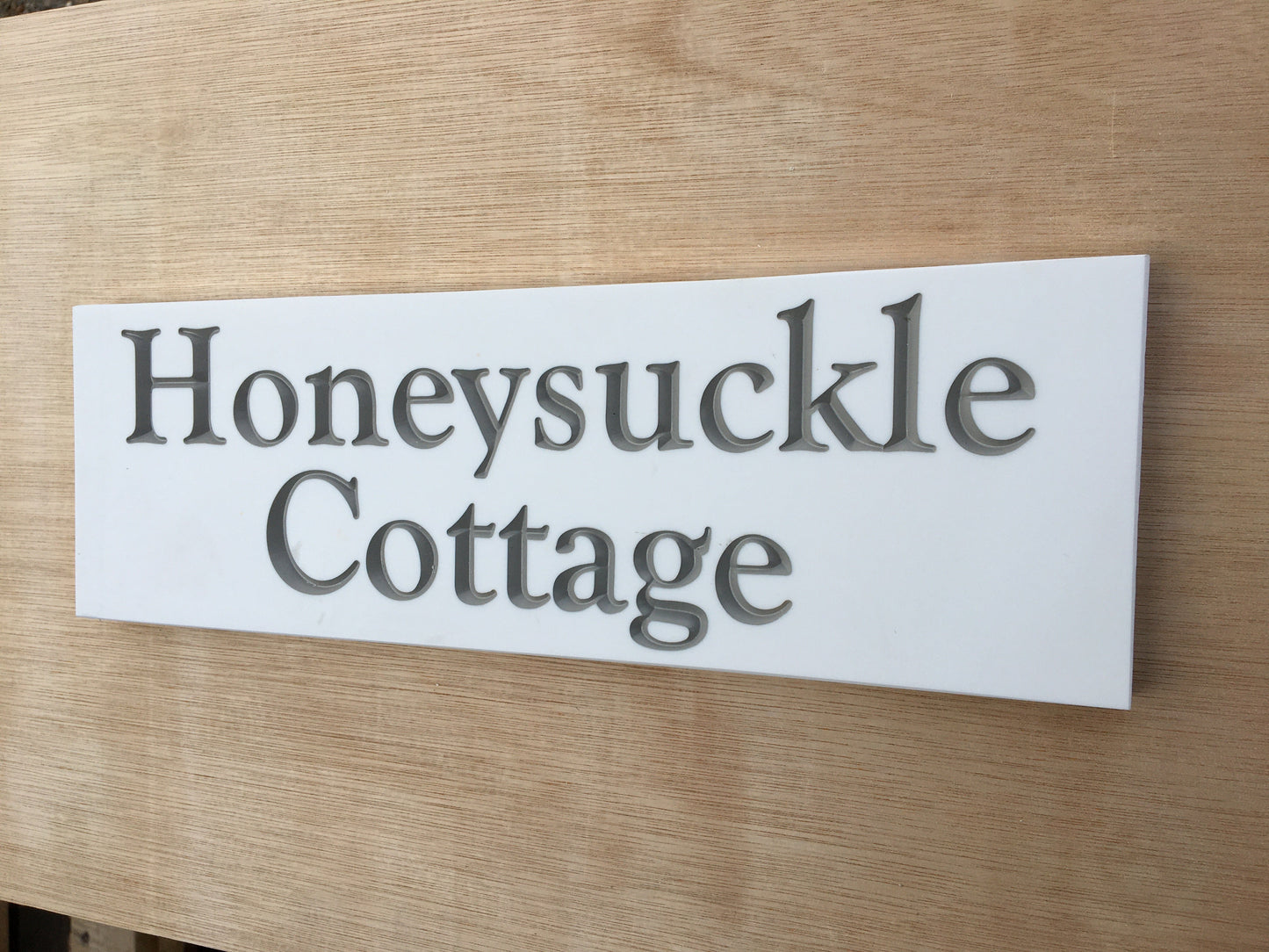 House sign measuring 300mm x 100mm using white Corian with the address deep engraved and infilled with grey monument paint