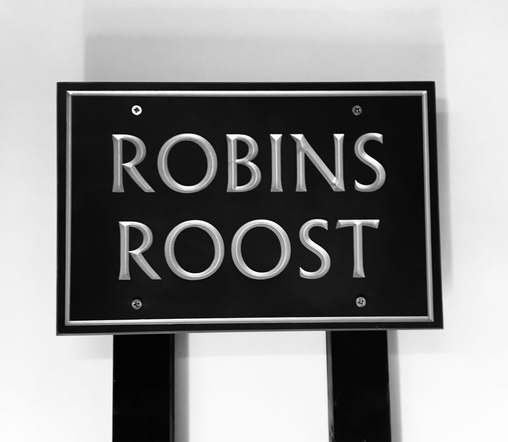 House sign measuring 300mm x 200mm using black Corian with a plain border and the house name  deep engraved and infilled with silver monument paint mounted on a black post 