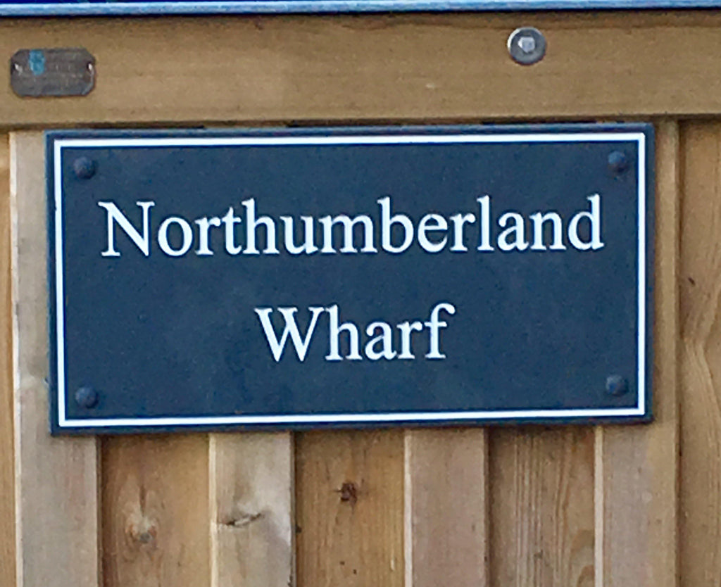 A slate house sign, measuring 200mm x 200mm, deep-engraved house name in Times New Roman font, on charcoal slate, enhanced with white paint. 
