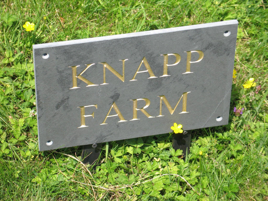 A grey slate house sign, dimensioned at 200mm x 100mm, featuring a deep-engraved house name in Times New Roman font. The engraving will be on grey slate, highlighted with gold paint.