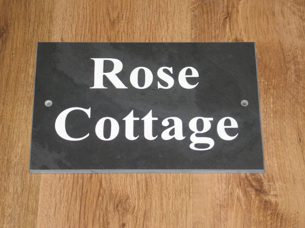 A slate house sign, measuring 200mm x 150mm, deep-engraved house name in Times New Roman font, on charcoal slate, enhanced with white paint.